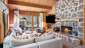 Interior acogedor de una cabaña con chimenea de piedra, techo de madera y un espacio de estar confortable.