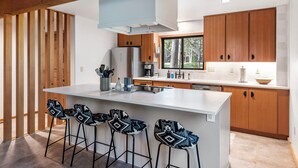 Una cocina moderna con armarios de madera, una isla central con taburetes altos y un ventanal que proporciona luz natural.