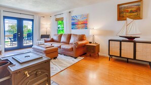 A living room with a leather sofa, a small cabinet, and a sailboat model on top. - Chirping Pines: Modern Lake Home on Cayuga Lake (Seneca Falls)