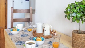 Ontbijt met koffie, sap en gebak op een tafel met een geweven onderzetter.