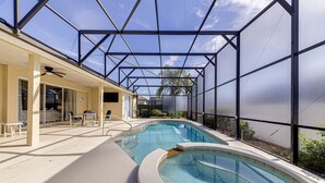 Une piscine dotée d’une structure servant de parasol, d’un espace extérieur aménagé pour s’asseoir et d’un patio couvert.