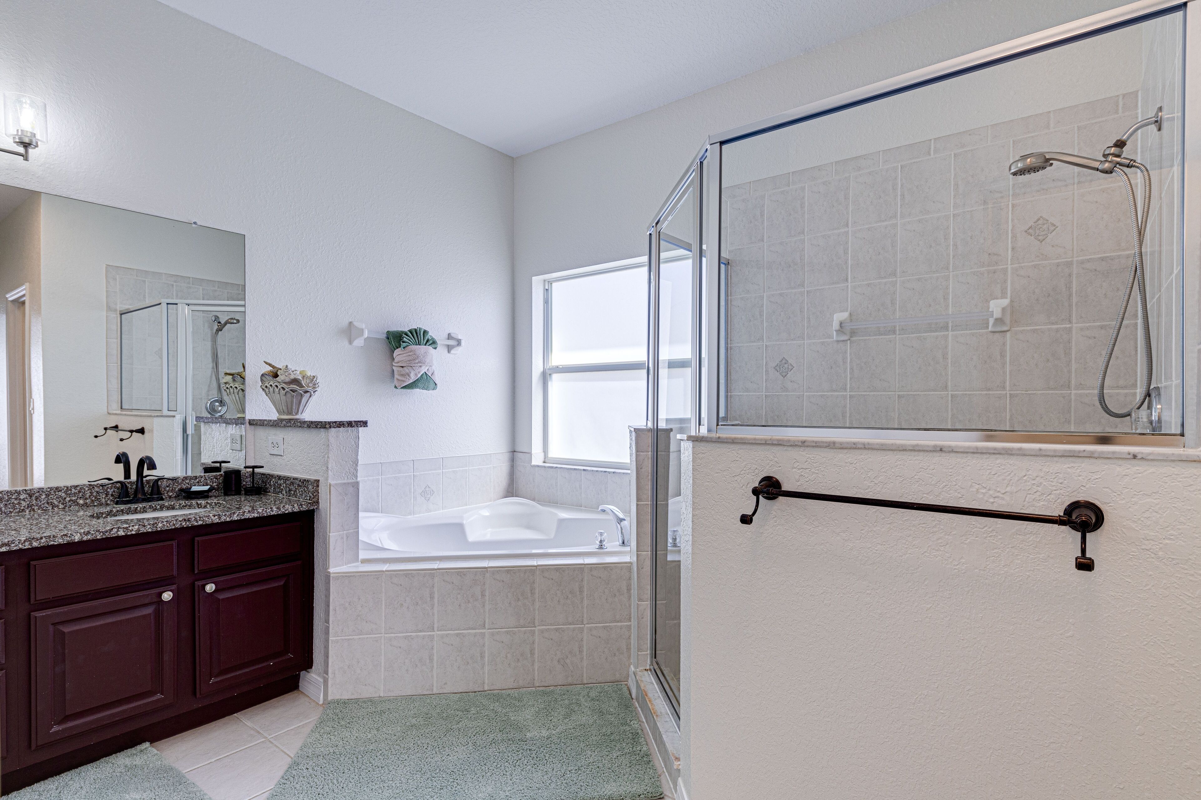 A bathroom with a shower, bathtub, and a vanity with a sink and mirror.