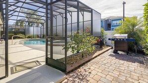 Une serre avec une piscine, un barbecue et un petit espace jardin.