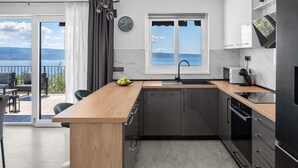 A modern kitchen with a wooden countertop, a built-in sink, and a view of the outdoors. - Seaview Villa Roko with heated pool (Jesenice, Dugi Rat)