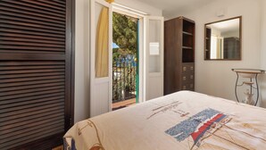 A bedroom with a bed, a wardrobe, a mirror, and a door leading to an outdoor balcony.