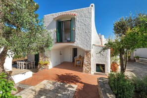 A white building with a stone facade, a balcony with green shutters, and a patio area with a table and chairs. - 3987 Villa Greco by Barbarhouse (Taranto)
