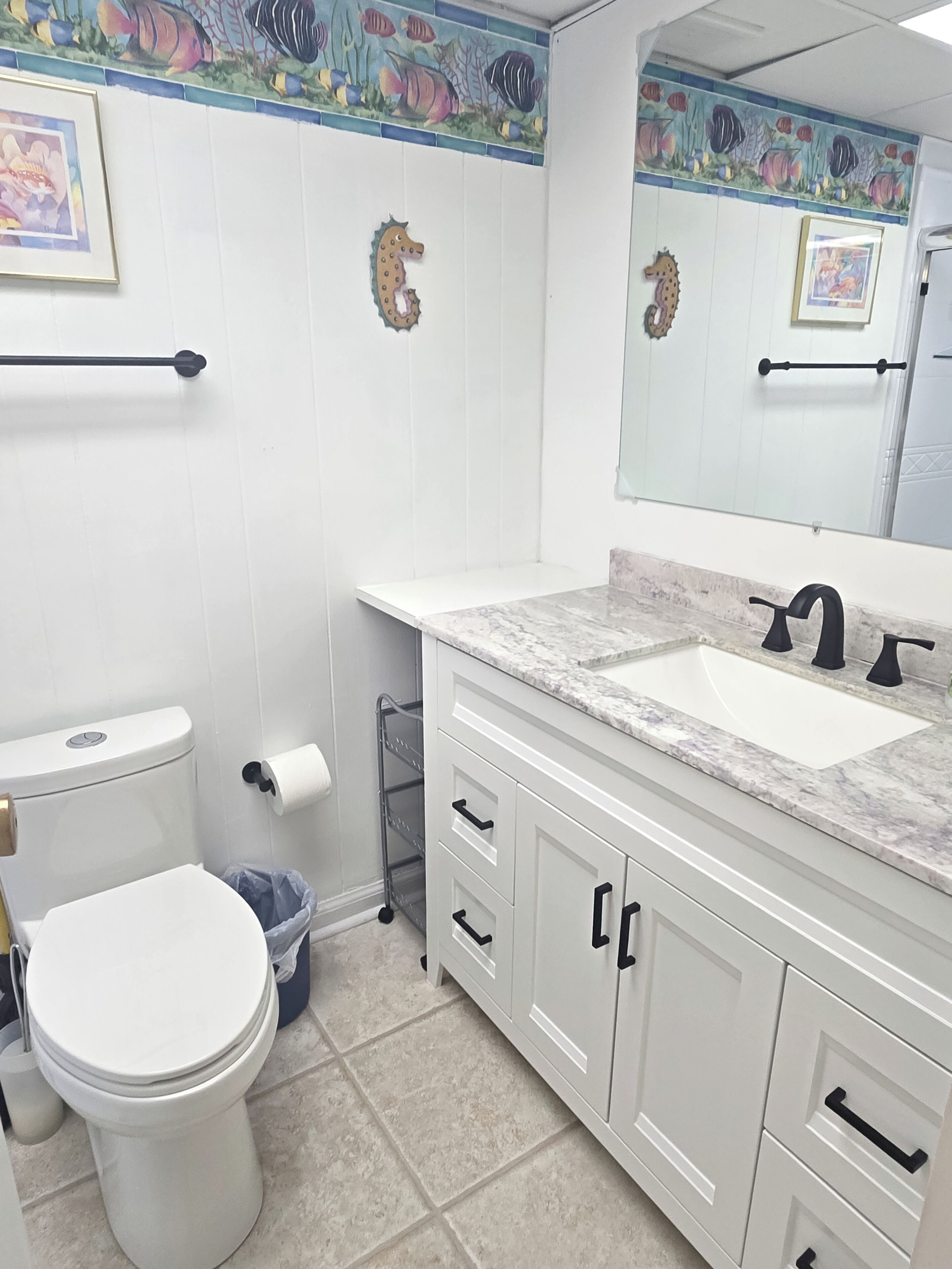 A bathroom with a toilet, sink, and vanity with drawers.