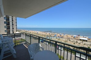 Un balcone con vista sulla spiaggia, arredi esterni e un edificio dal design moderno.