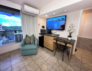 Een moderne woonkamer met een bank, een bureau, een stoel, een televisie en een balkon met uitzicht.