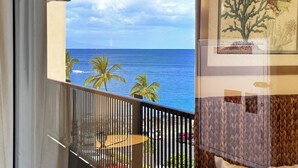 Een balkon met uitzicht op de oceaan en palmbomen.