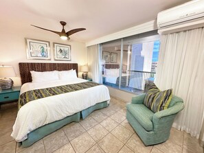 Een hotelkamer met een bed, een plafondventilator, een balkon met gordijnen en een airconditioning.