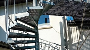 Metallikaiteilla varustettu kierreportaisto, joka johtaa ylempään kerrokseen.