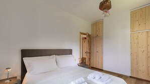 Un lit bien fait, avec du linge de lit et des serviettes blanches, une lampe de chevet et une armoire en bois.