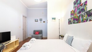 Ein Hotelzimmer mit Bett, Fernseher, Schreibtisch und Bildern an der Wand.