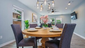A dining area with a round table, six chairs, and a chandelier. - Spacious Delightful 4 BR/ 3 BA Close to Downtown (San Antonio)
