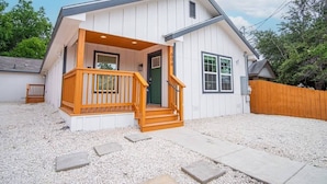A single-story house with a front porch, a green door, and a wooden fence. - Spacious Delightful 4 BR/ 3 BA Close to Downtown (San Antonio)