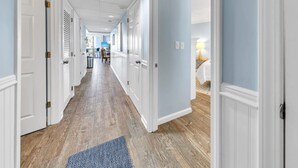 A hallway with white doors, wooden flooring, and a blue rug. - ⛵Stunning Gulf Front-Lagoon Pool-Edgewater 1-105⛵ (Panama City Beach)