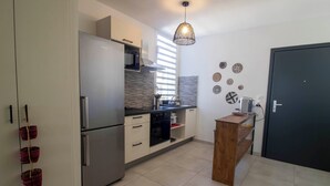 A modern kitchen with stainless steel appliances, a wooden island, and decorative wall art. - EVASION SAINT LEU, APARTMENT 100 M FROM THE SEA  (Saint-Leu)