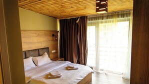A bedroom with a wooden headboard, a bed with white linens, a nightstand, and a window with curtains.