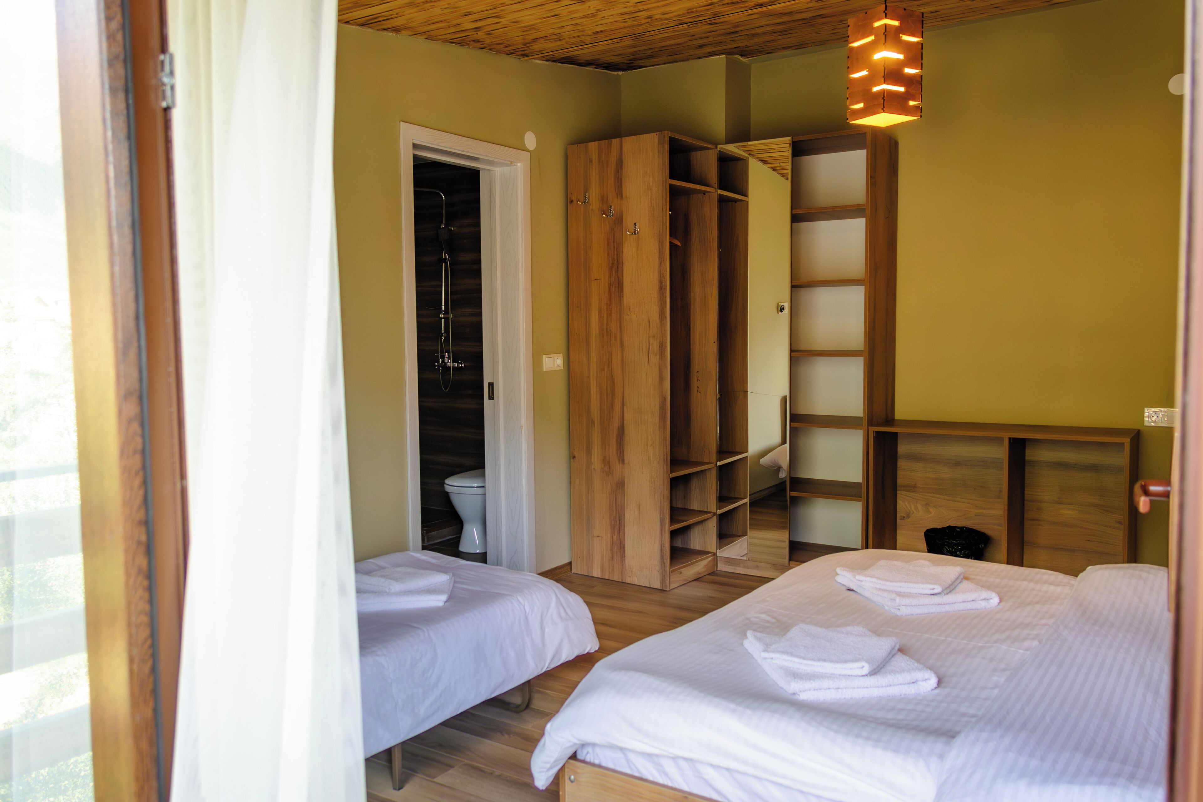 Een kamer met twee bedden, een houten garderobe, een badkamer met toilet en douche.