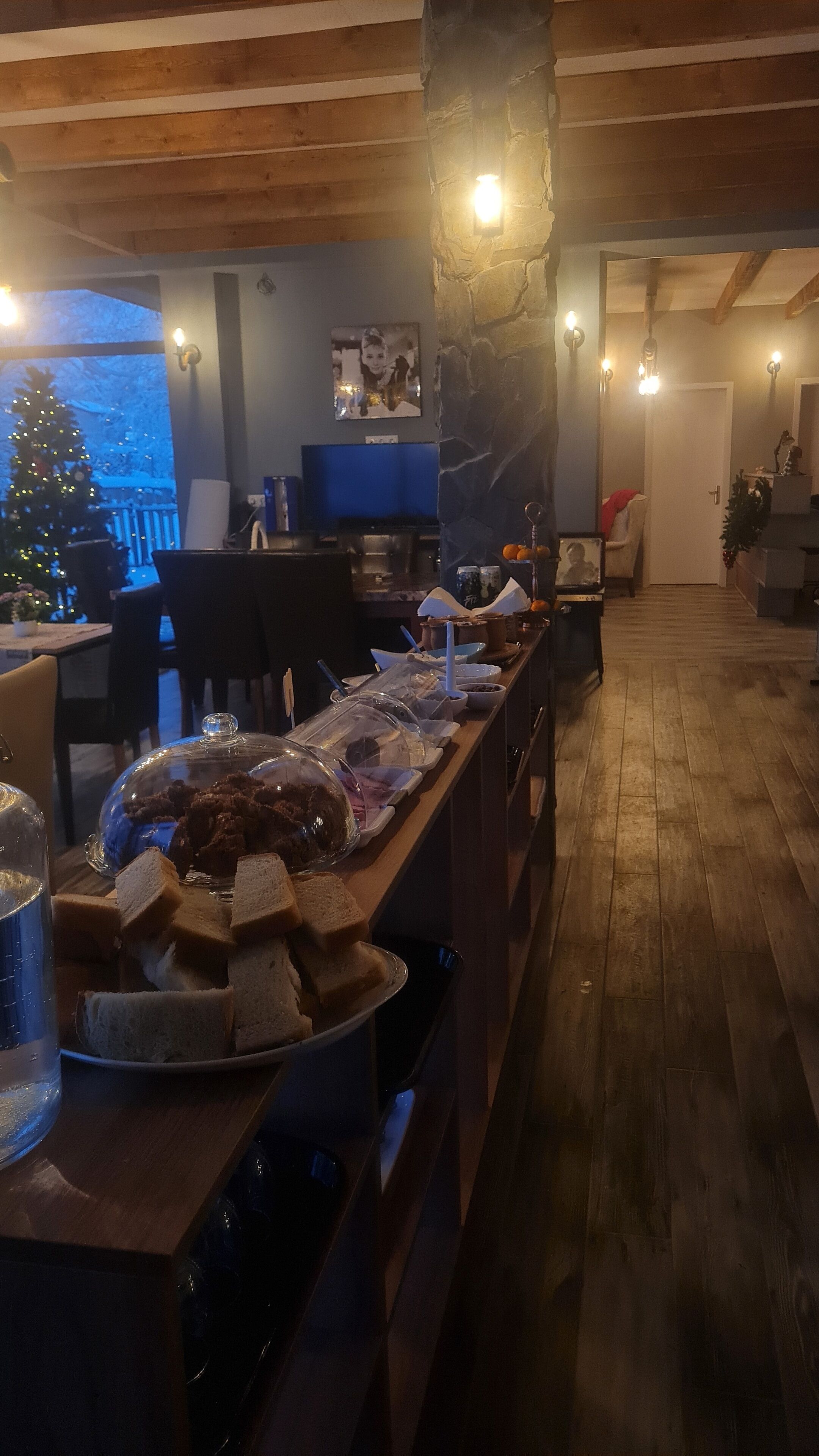 Tunnelmallinen ravintola, jossa on pitkä puinen tiski, kivipilari ja taustalla joulukuusi.