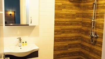 A bathroom with a wooden wall, a white sink, and a shower.