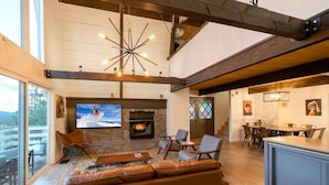 A spacious living room with a fireplace, comfortable seating, a television, and a view of the outdoors.