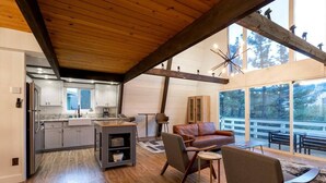 A modern kitchen with a built-in island, a dining area with a leather couch, and a large sliding glass door leading to an outdoor deck.