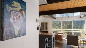 A modern interior with a large abstract painting, a wooden ceiling, and a view of the outdoors.