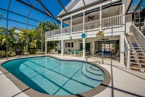 A pool area with a glass ceiling, a two-story building with a balcony, and outdoor seating.