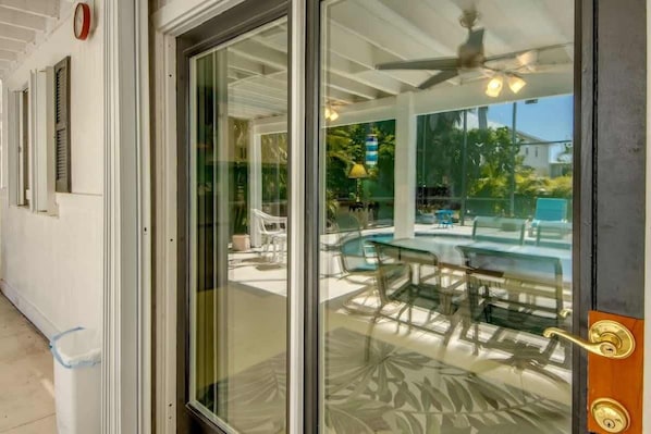 A glass door leading to an outdoor patio with a pool and seating area.