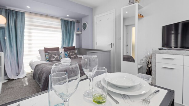 A modern hotel room with a dining area, a bed with a view, and a TV. - Boutique Studio Apartment By My Getaways (Brighton)