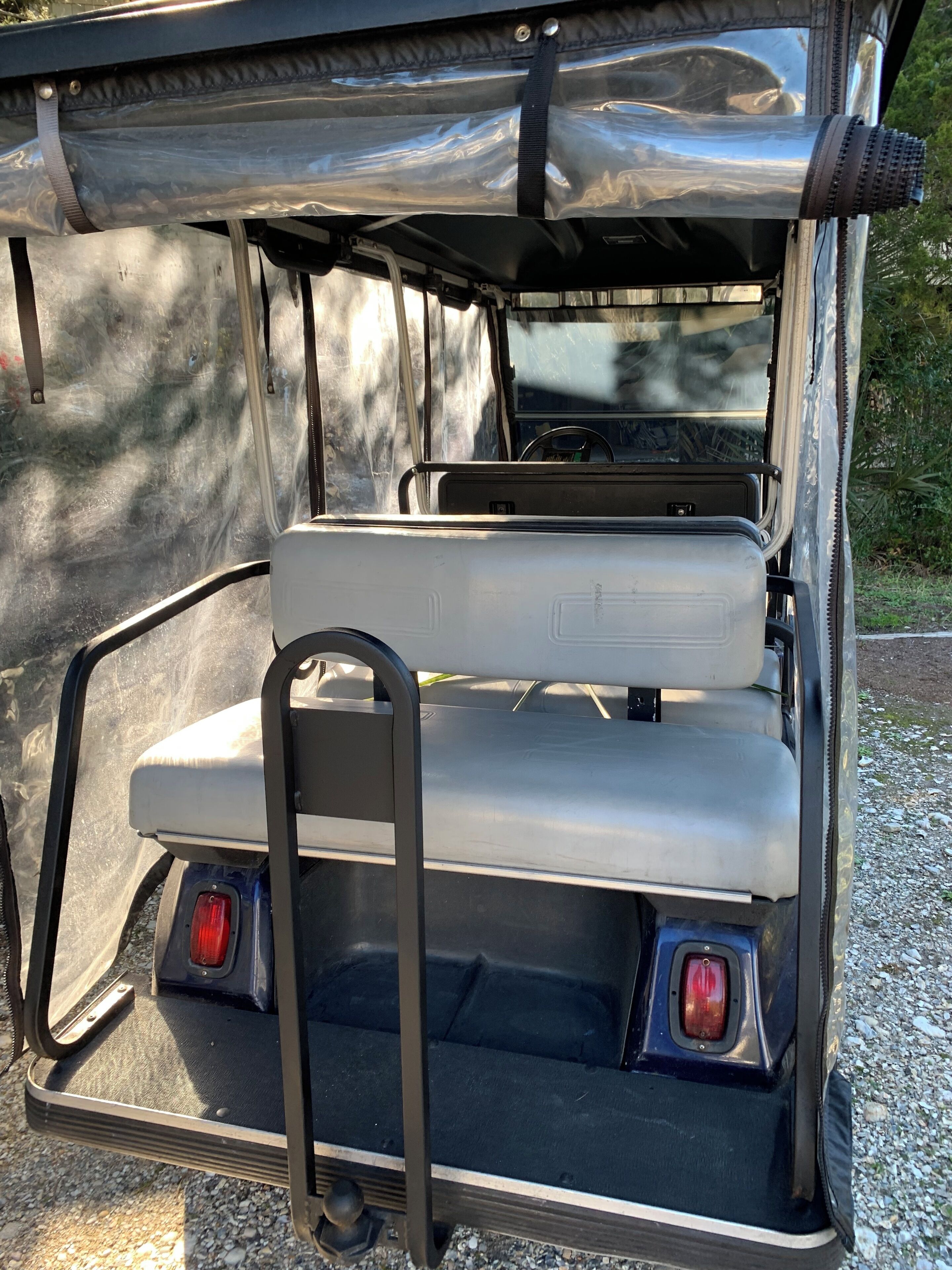 Ein Golfmobil mit überdachter Sitzgruppe und einem Metalltritt.