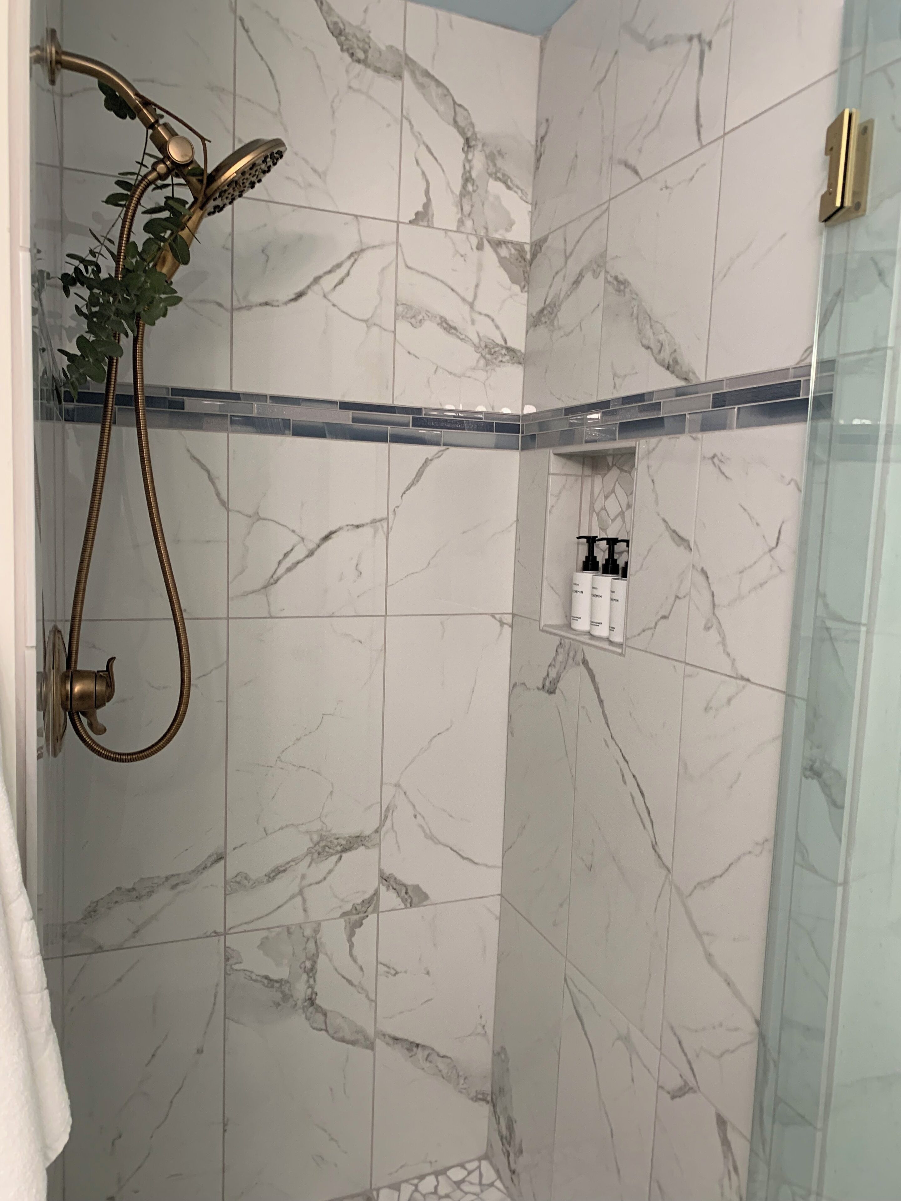 A shower with a handheld showerhead and a wall-mounted control.