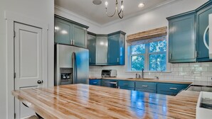 A kitchen with teal cabinets, a stainless steel refrigerator, and a wooden countertop. - Beautiful Home in Seagrove Beach “The Chart House”, Close to Seaside and 7 minut (Santa Rosa Beach)