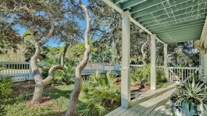 A covered outdoor area with a wooden deck, surrounded by trees and potted plants. - Beautiful Home in Seagrove Beach “The Chart House”, Close to Seaside and 7 minut (Santa Rosa Beach)
