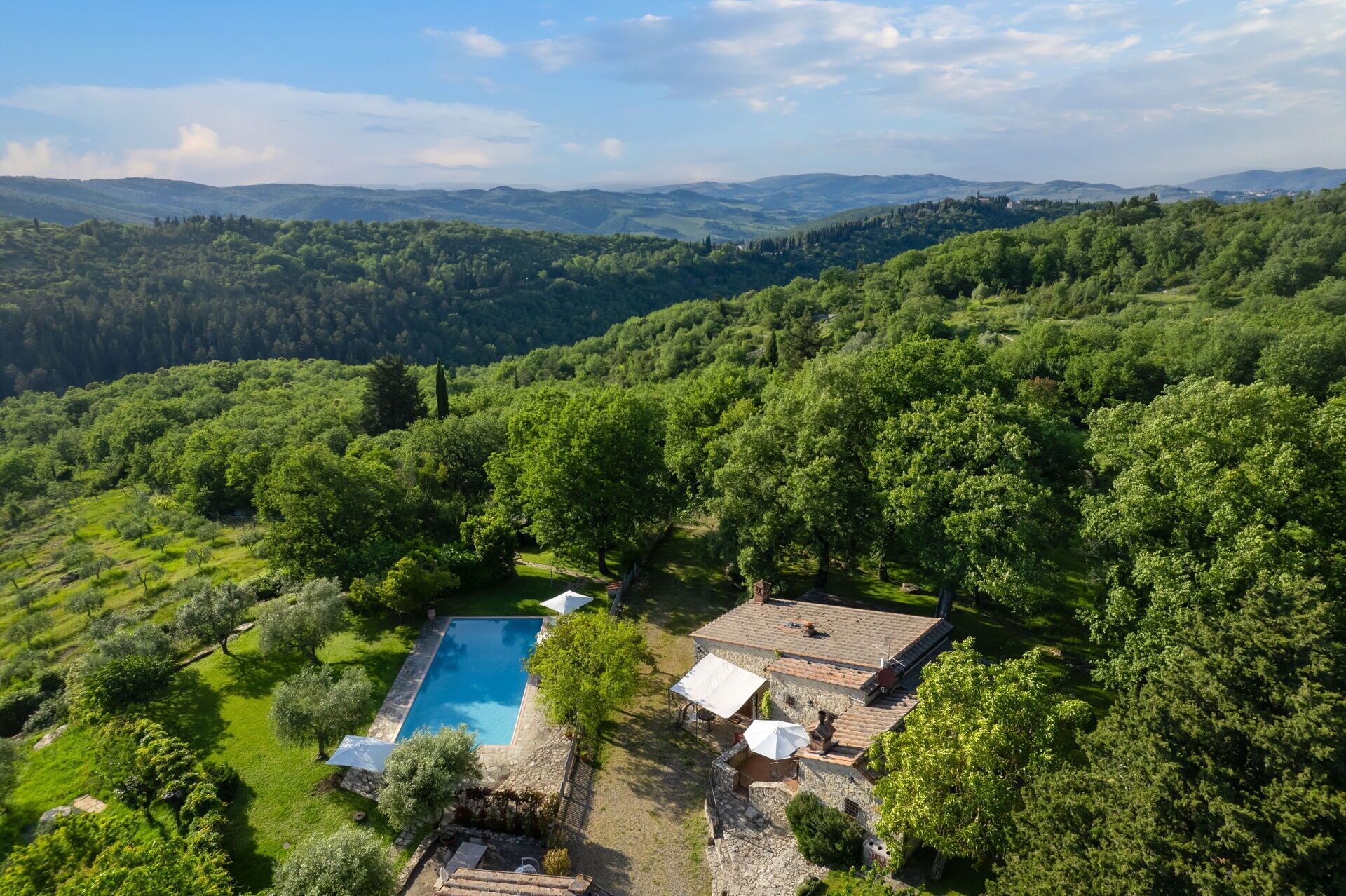 Una villa con piscina circondata da rigogliosa vegetazione e colline.