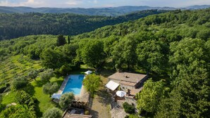 Una villa con piscina rodeada de exuberante vegetación y colinas.