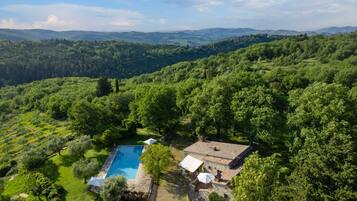Una villa con piscina circondata da rigogliosa vegetazione e colline.