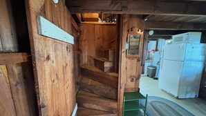 A wooden staircase leading to a kitchen area with a refrigerator and a microwave.