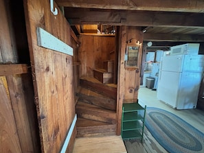 A wooden staircase leading to a kitchen area with a refrigerator and a microwave.