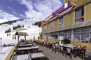 A restaurant with outdoor seating overlooking a snowy mountain. - Resort center, view mountain, tv, ski locker, 25-30m², Orcières Merlette 1850 (Orcières)