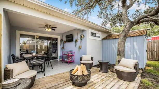 A covered patio with wicker furniture, a fire pit, and a dining area with chairs and a table.