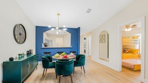 A modern living room with a dining area, a blue accent wall, and a large mirror.