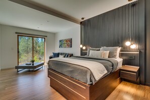 A modern bedroom with a large bed, a bench, and a view of trees through a sliding door. - Modern Marvel - Incline Village - TLUXP (Incline Village)