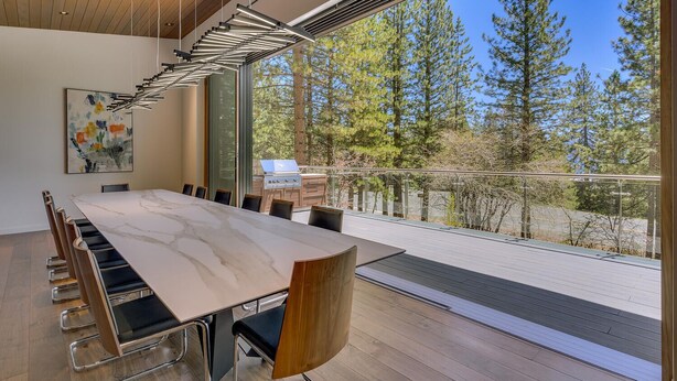 A modern meeting room with a large table, chairs, and a view of trees through large windows. - Modern Marvel - Incline Village - TLUXP (Incline Village)