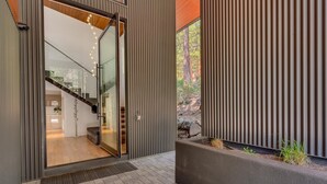 A modern building entrance with a glass door leading to a staircase and a view of a forested area. - Modern Marvel - Incline Village - TLUXP (Incline Village)