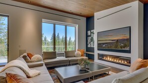A modern living room with a fireplace, large windows, and a view of the outdoors. - Modern Marvel - Incline Village - TLUXP (Incline Village)