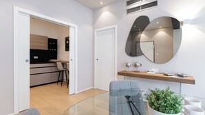 Una sala de estar moderna con una mesa de centro de vidrio, un sillón gris y una pequeña planta en maceta.