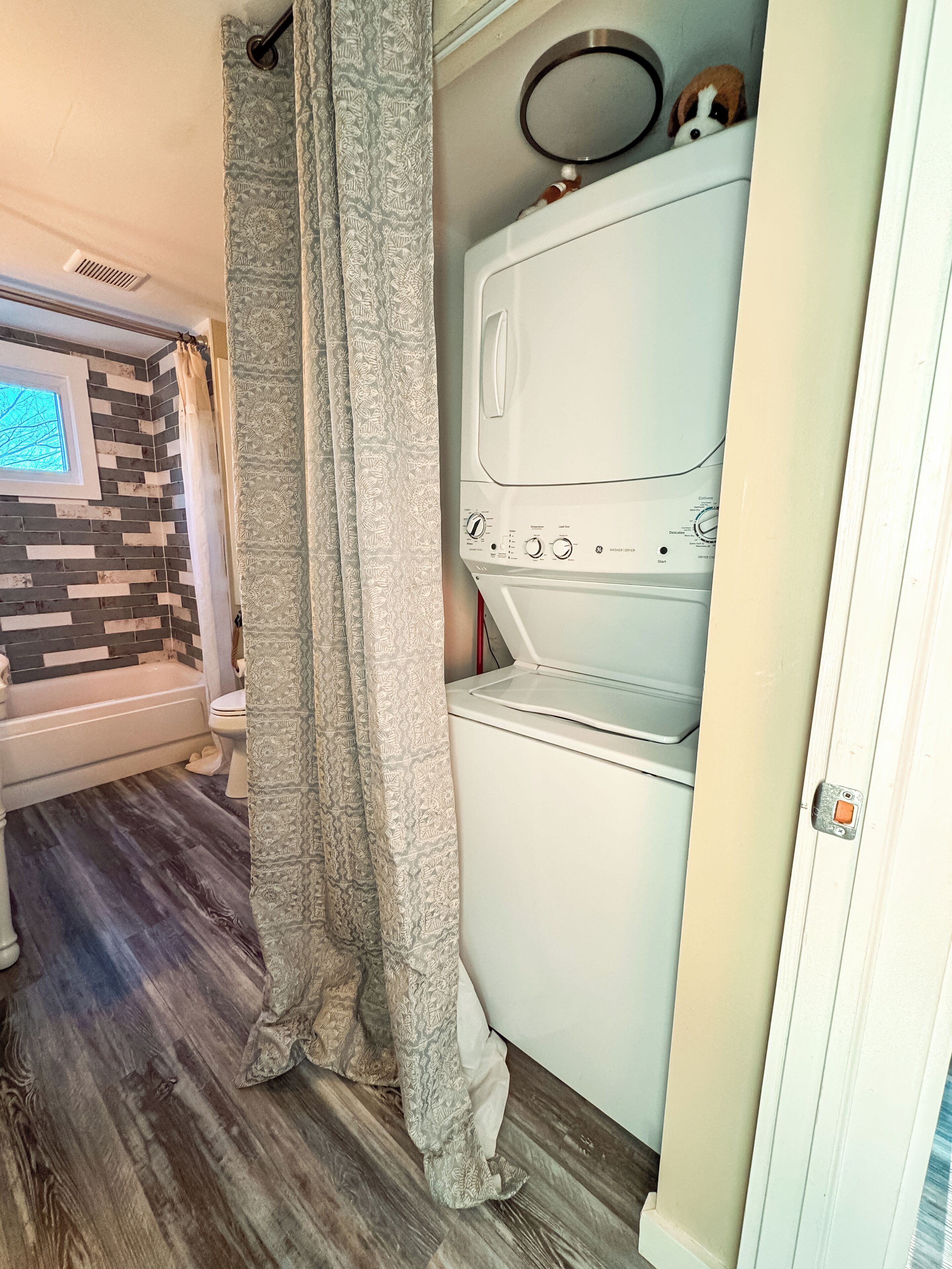 A compact bathroom with a shower, toilet, and built-in washer-dryer unit.
